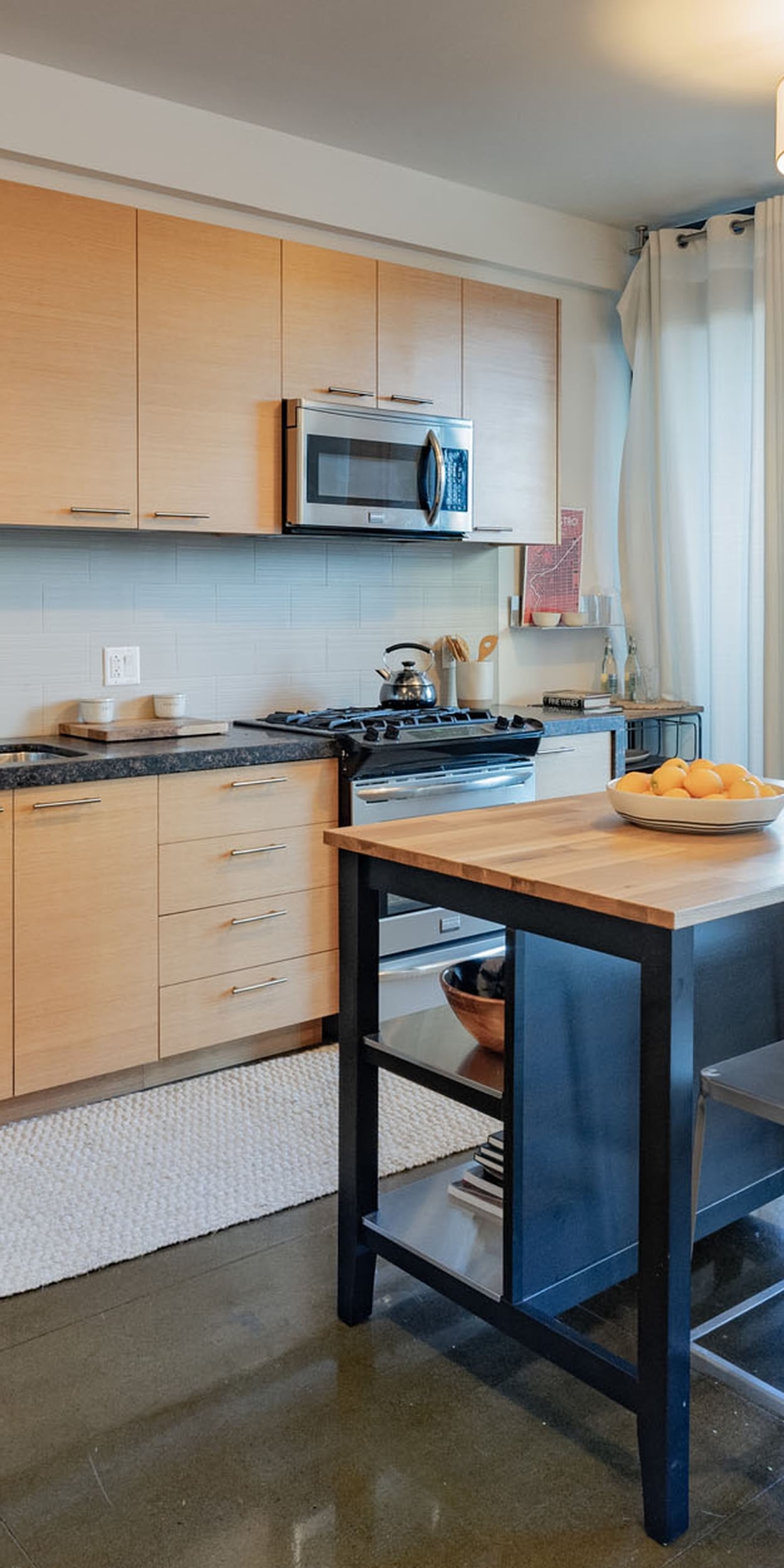 Dogpatch CA Apartments- Sleek Modern Kitchen With Concrete Floors, Granite Countertops, Stylish Wood Cabinets, and Stainless Steel Appliances